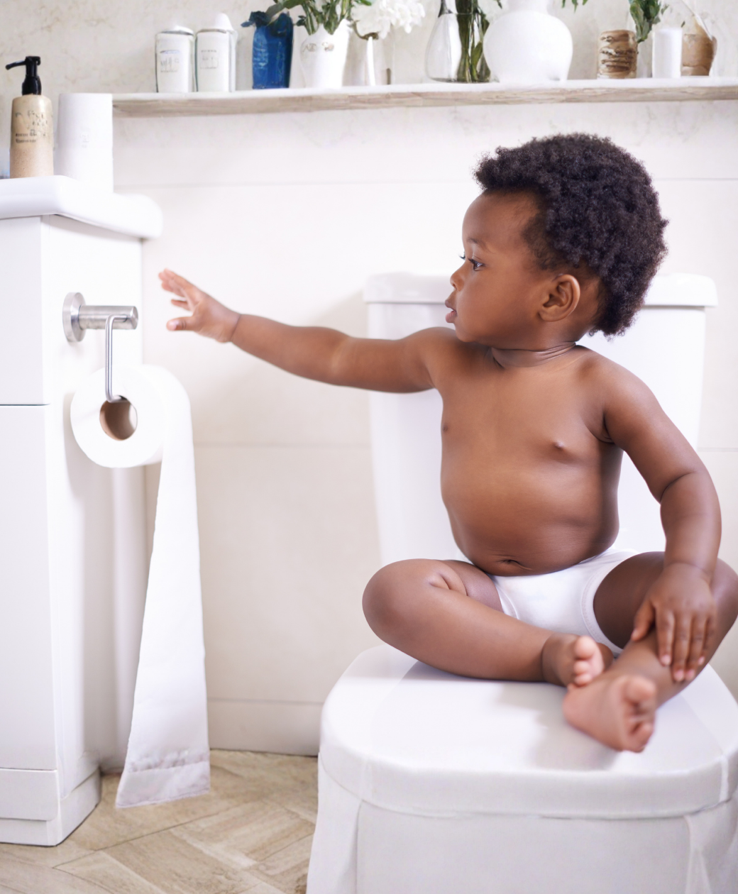 Toddler reaching for toilet paper during nighttime potty training in bathroom